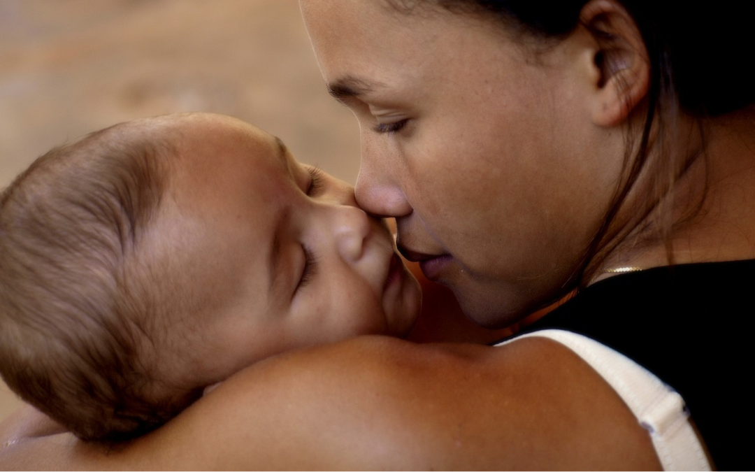 Mother holding a baby and pinching her nose while struggling with postpartum depression